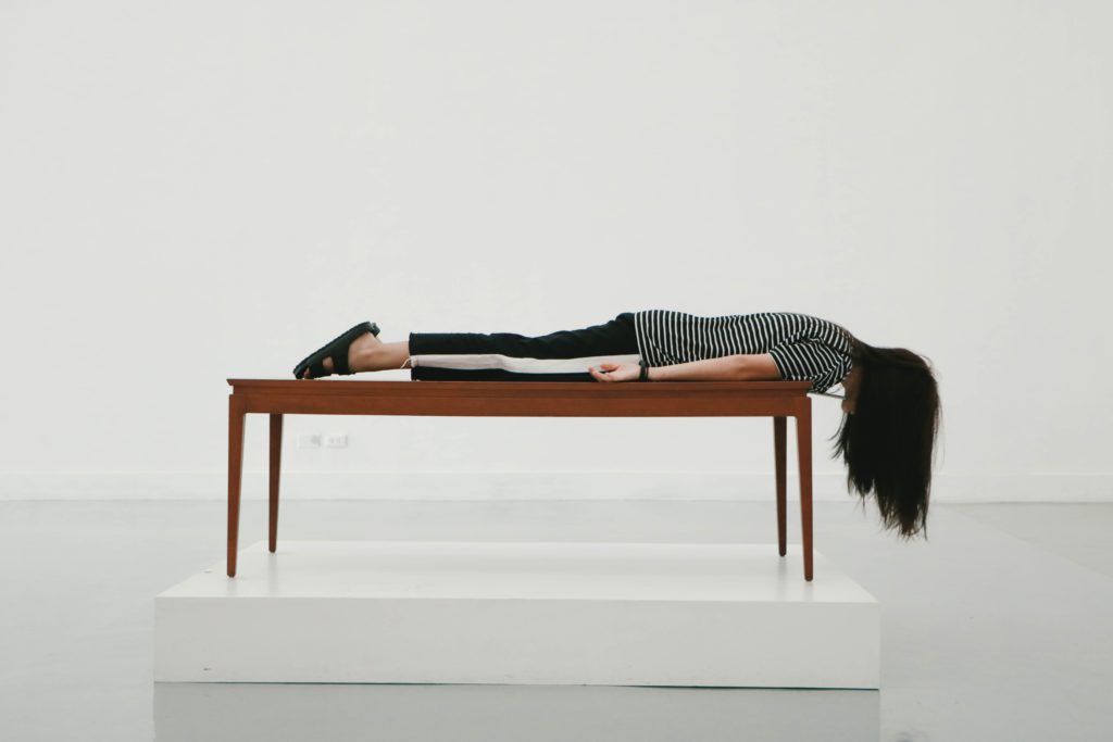 A woman lying upside down off of a table