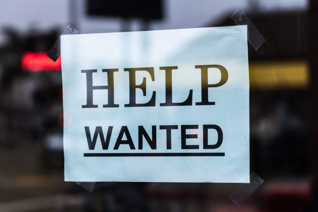 Sign in window stating: Help Wanted. Photo Credit: Tim Mossholder on Unsplash.