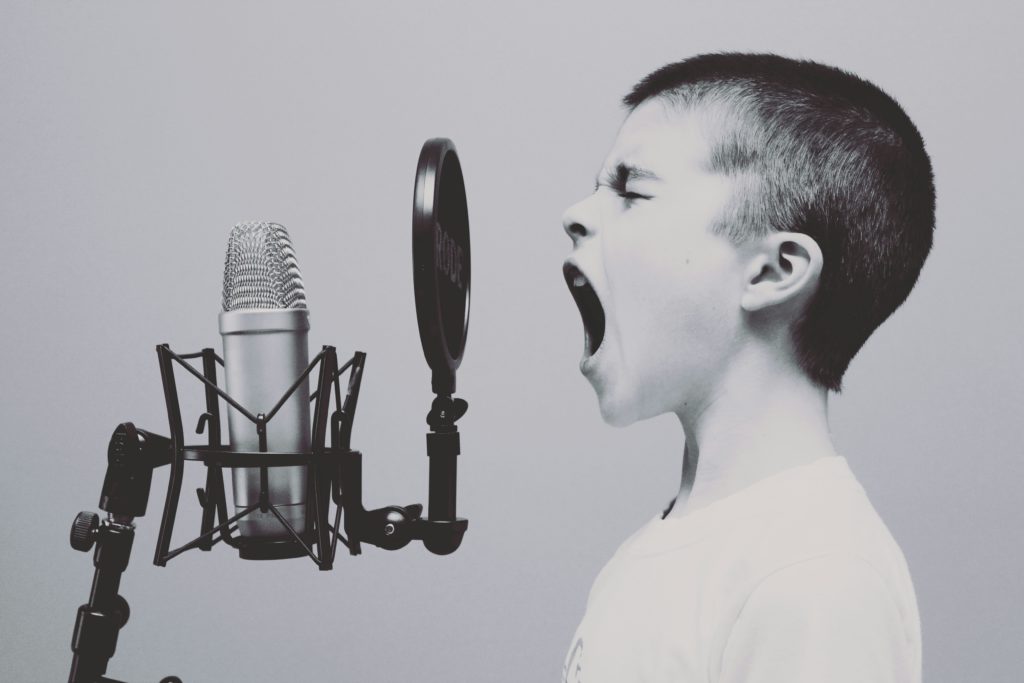 black and white photo of a boy talking into an old timey microphone to emphasize the importance of author voice