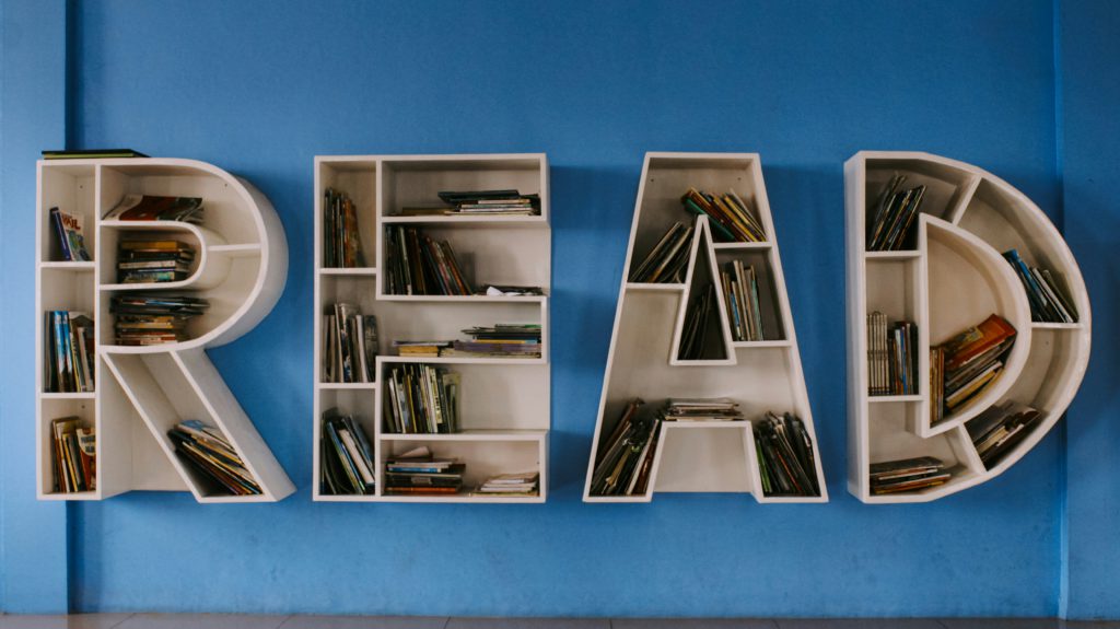 White bookshelf shaped as the word "Read" against a blue wall.