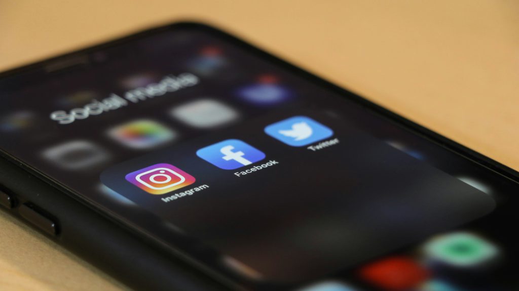 An image of a phone with instagram, facebook, and twitter pulled up to emphasize the importance of social media in building writing conference credentials.